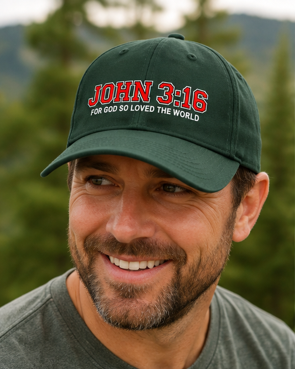 A smiling man wearing a dark green baseball cap with red and white embroidered text reading 'JOHN 3:16 FOR GOD SO LOVED THE WORLD' against a blurred outdoor background of trees and hills.